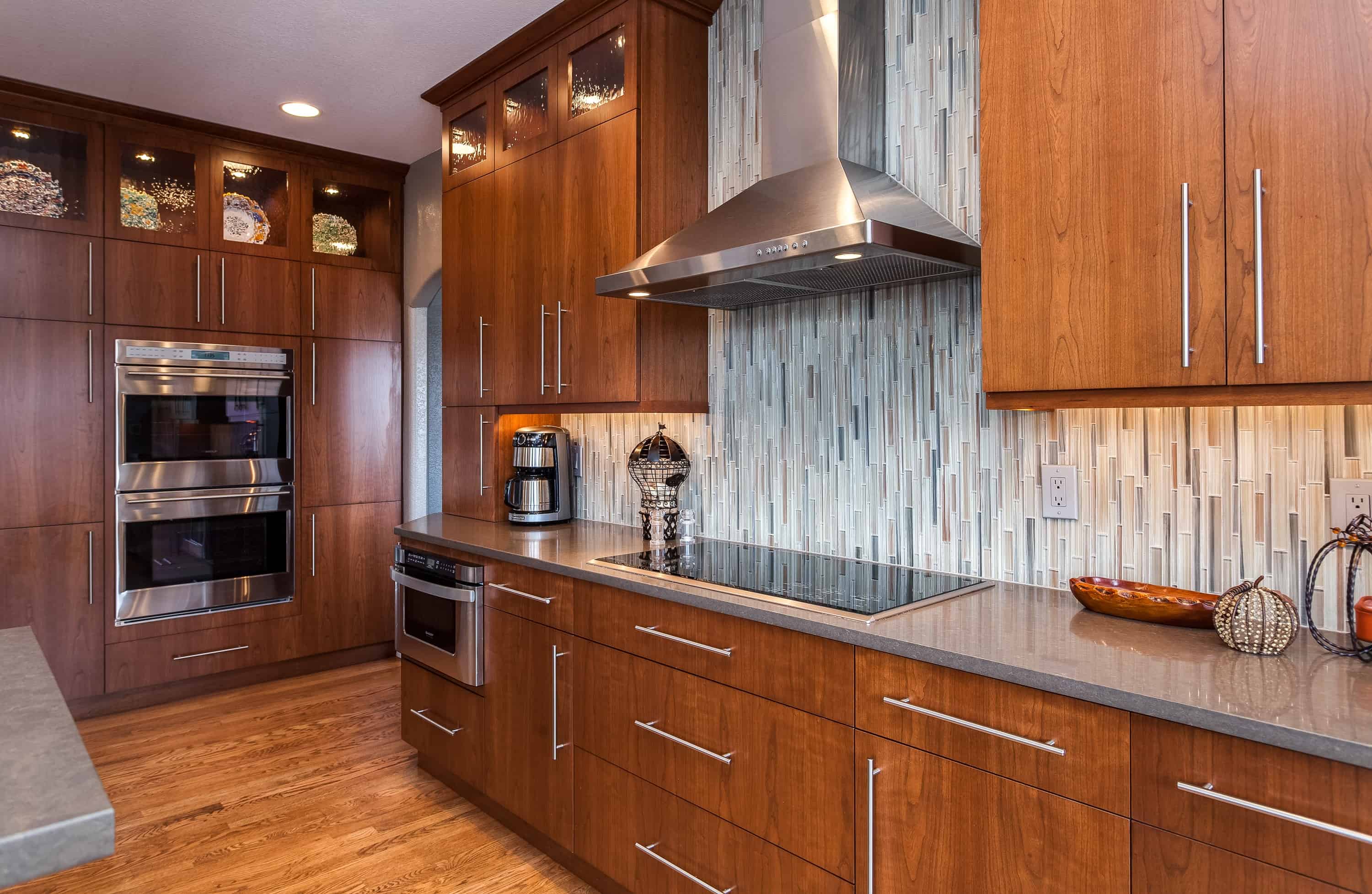 Natural wood cabinets with glass tile backsplash