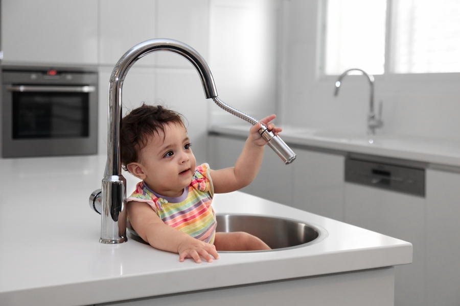 cute kid sitting in the kitchen sink